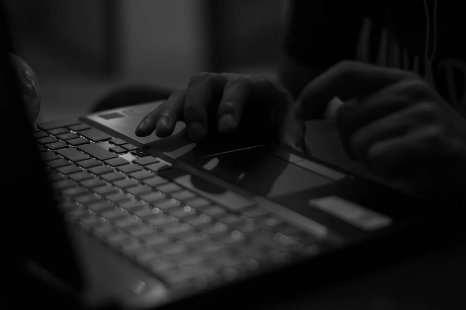 Person som skriver på en laptop i ett mörkt rum, illustrerar dold AI-användning